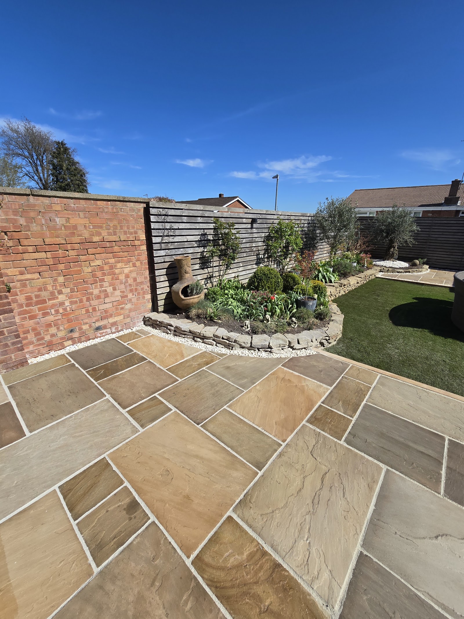A newly laid Indian sandstone patio with fresh planting and timber fencing in a Solihull garden