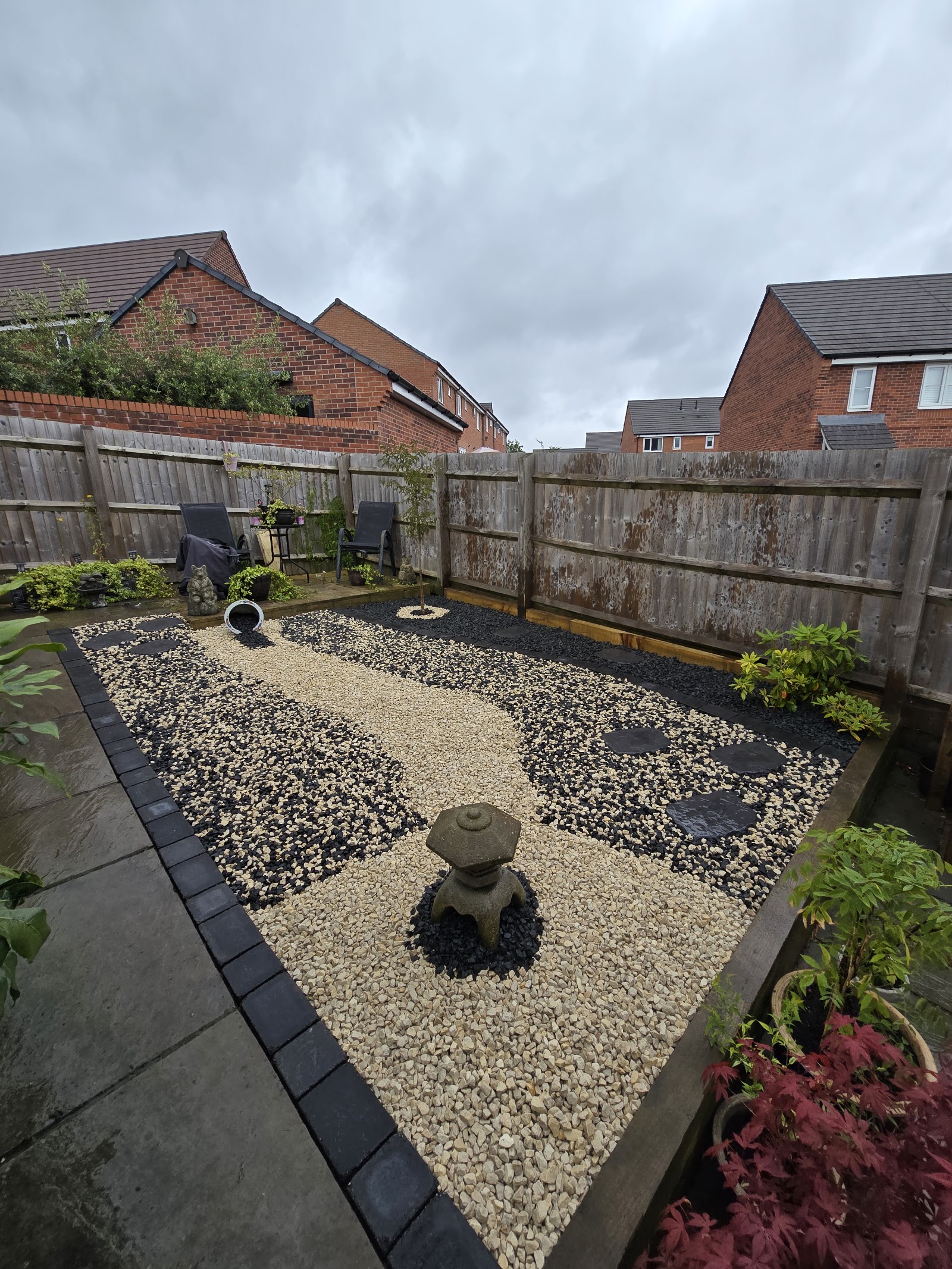 A landscaped gravel garden with two-tone stone, a stone lantern water feature and a new fence line